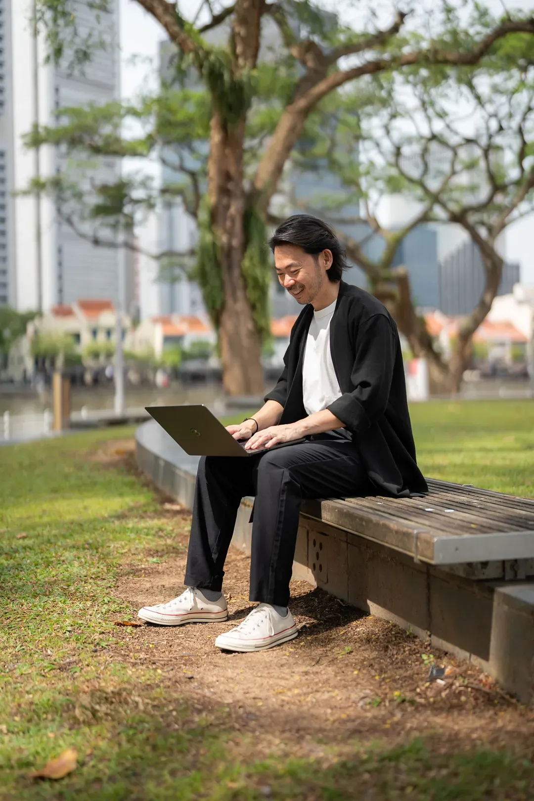 Gerald Ang working on a laptop in a park